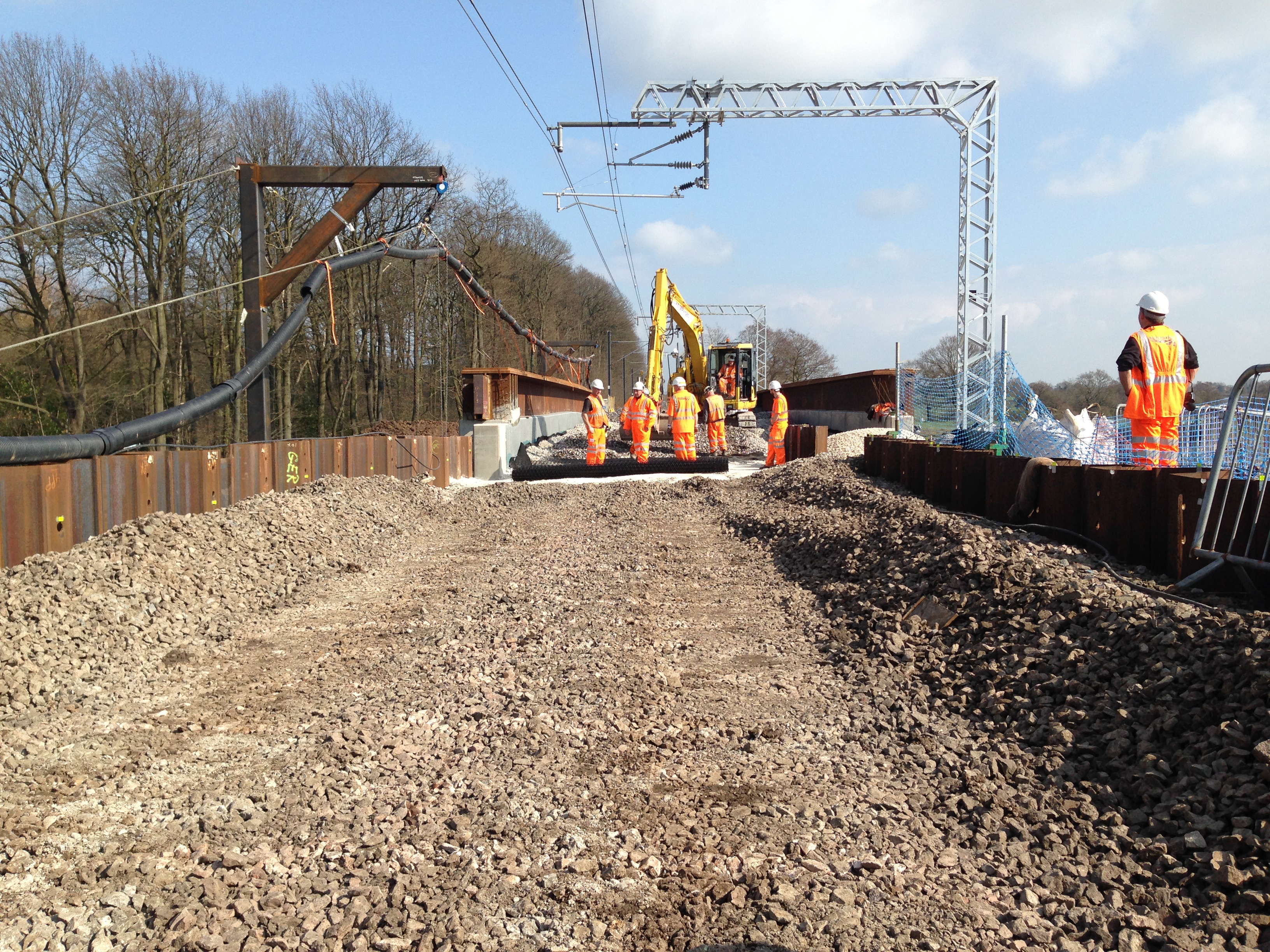 Rail embankment civils works with excavator and crew.