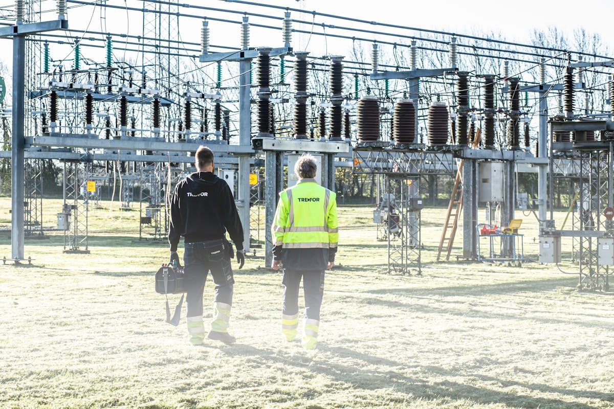 Utility engineers walking into a high-voltage substation at dawn.