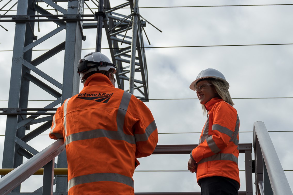 Network Rail engineers on a platform with feeder station infrastructure overhead.