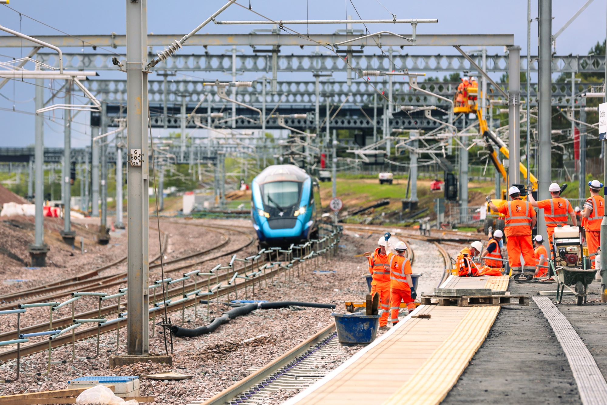Network Rail engineers in hi-vis with overhead line equipment behind.